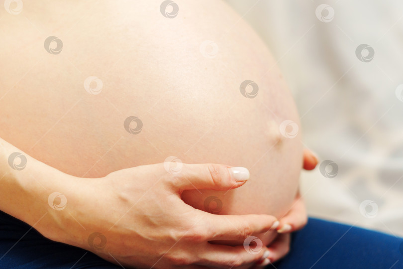 Скачать Крупный план живота беременной женщины в третьем триместре. Ожидание ребенка. Концепция любви, счастья и безопасности. фотосток Ozero