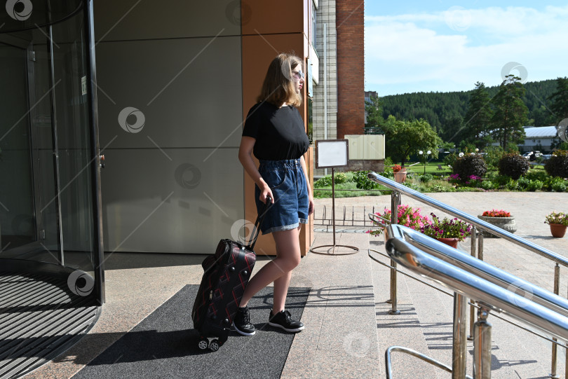 Скачать Элегантная девушка с багажом в вестибюле отеля. Женщина с чемоданом в отпуске или путешествии. фотосток Ozero