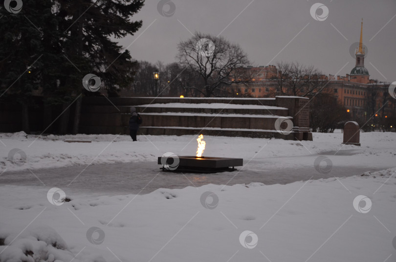 Скачать Санкт-Петербург, Россия – 24.12.2023: Вечный огонь на Марсовом поле в Санкт-Петербурге зимой, на заднем фоне Инженерный замок фотосток Ozero