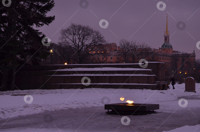 Скачать Санкт-Петербург, Россия – 24.12.2023: Вечный огонь на Марсовом поле в Санкт-Петербурге зимой, на заднем фоне Инженерный замок фотосток Ozero