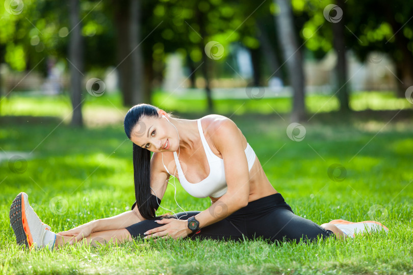 Скачать Красивая спортивная женщина делает упражнения на растяжку в городском парке на зеленой траве. Позы йоги фотосток Ozero
