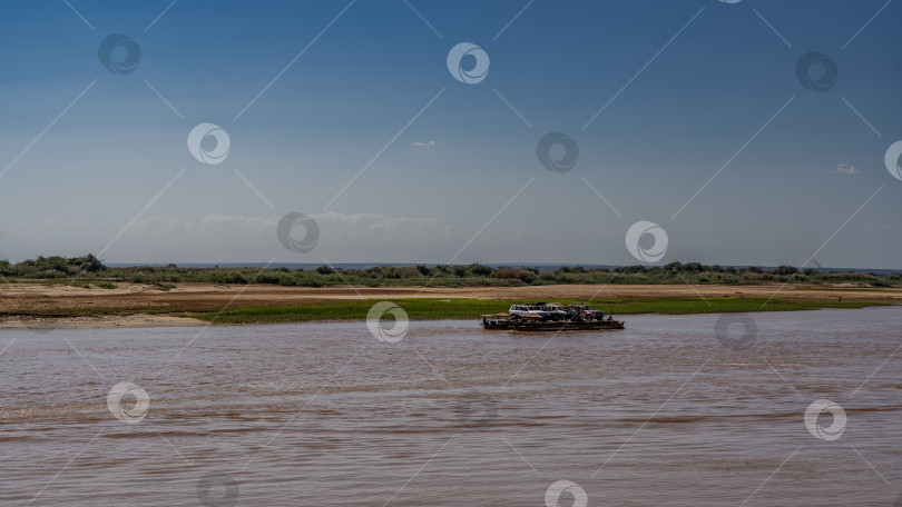 Скачать По красно-коричневой реке плывет паром, груженный автомобилями фотосток Ozero