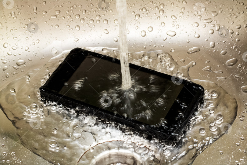 Скачать Прикоснитесь к мобильному телефону под струей воды из-под крана крупным планом фотосток Ozero