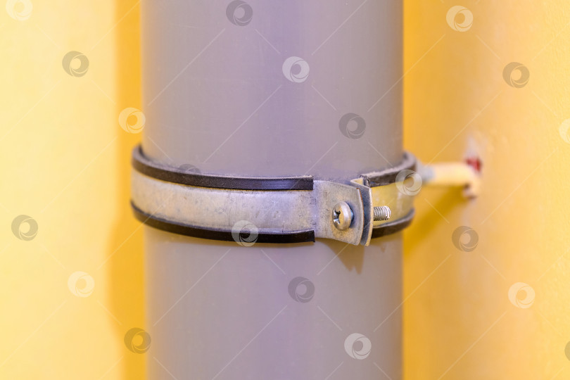 Скачать Канализационная труба в доме на фоне желтой стены в туалете. Соединение серых полипропиленовых труб для умывальника, унитаза, сливного бачка для раковины фотосток Ozero