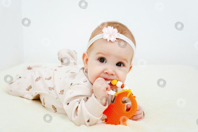 Скачать Малыш лежит и жует игрушку для прорезывания зубов. фотосток Ozero