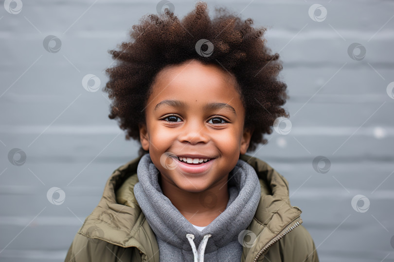Скачать Портрет детского образа жизни, улыбающийся афроамериканский мальчик в повседневной одежде на фоне стены на открытом воздухе, смотрящий в камеру фотосток Ozero