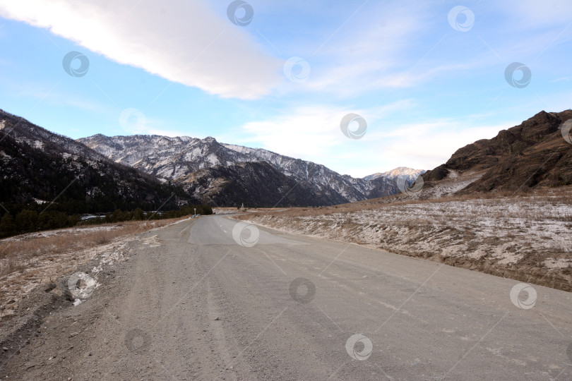 Скачать Перекресток грунтовых и асфальтированных дорог в живописной зимней долине, окруженной заснеженными горами. фотосток Ozero