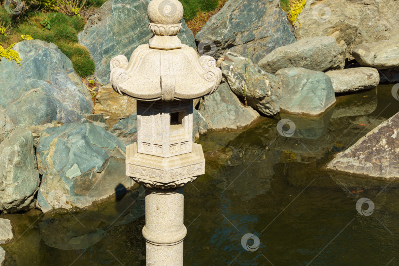 Скачать Традиционная японская каменная лампа, снежный фонарь Юкими Торо в японском саду общественного ландшафтного парка Краснодара или парка Галицкого, Россия фотосток Ozero