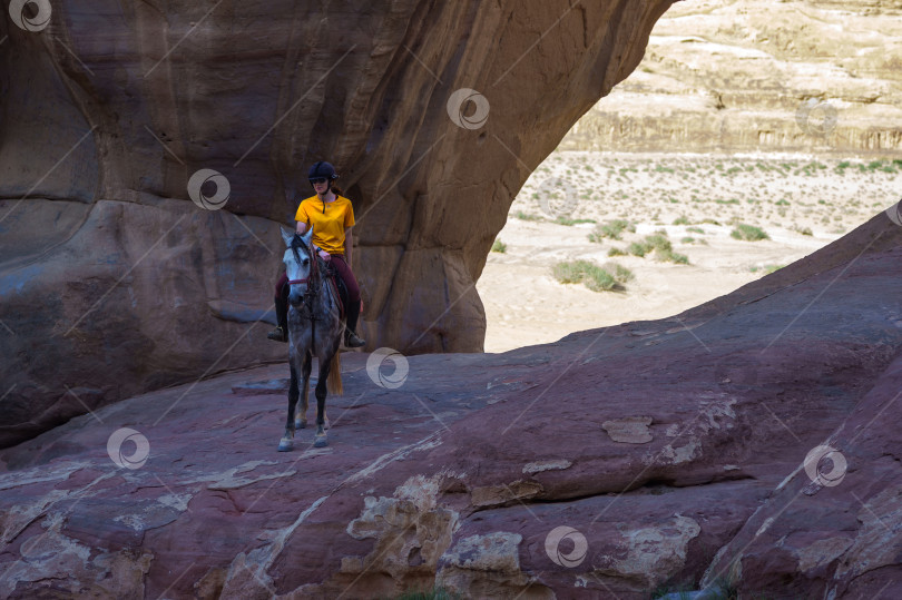 Скачать Иордания. Пустыня Вади-Рам - это настоящий Марс на Земле и национальный парк в Иордании. Девушка на лошади на фоне фантастических пейзажей со скалами причудливой формы. фотосток Ozero