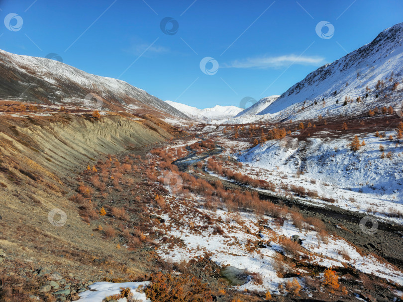 Скачать Сухое русло реки осенью в горной долине. Первый снег в горах. Солнечный прекрасный день, горный пейзаж. фотосток Ozero