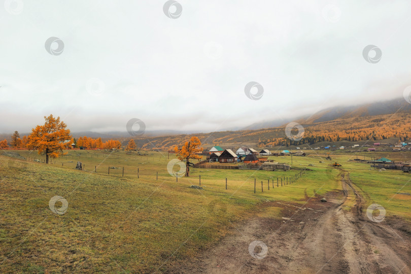 Скачать Осенняя грунтовая дорога с холма в отдаленную деревню. Бездорожье фотосток Ozero