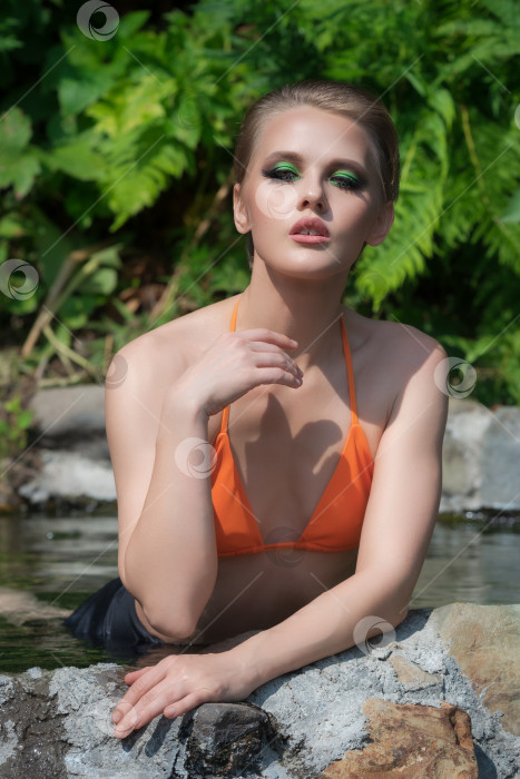 Скачать Блондинка, расслабляющаяся в бассейне с природной геотермальной водой на открытом воздухе, делает акцент на чувственной внешности фотосток Ozero