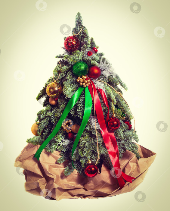 Скачать Рождественская елка, завернутая в крафтовую оберточную бумагу в качестве подарка на Рождество и Новый год. Изолированный фотосток Ozero