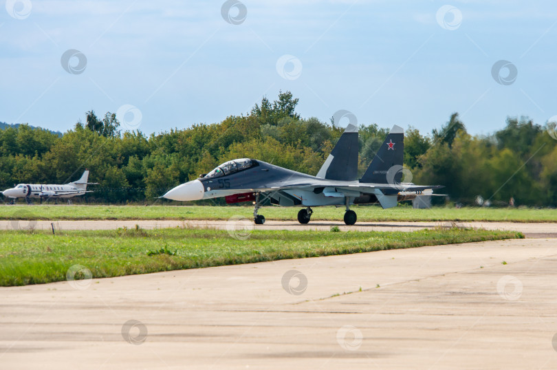 Скачать МАКС-2013. Крупный план. Советско-российский многоцелевой истребитель Су-27 (НАТО - Flanker-C) 4-го поколения с ракетами класса "воздух-воздух" на крыле, пилоты рулят по взлетно-посадочной полосе. фотосток Ozero