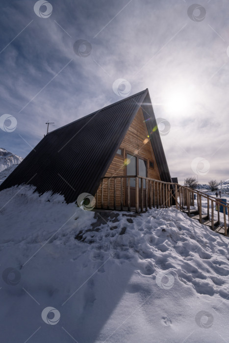 Скачать Вертикальный снимок деревянного коттеджа, окруженного снегом. Зона отдыха в горах фотосток Ozero