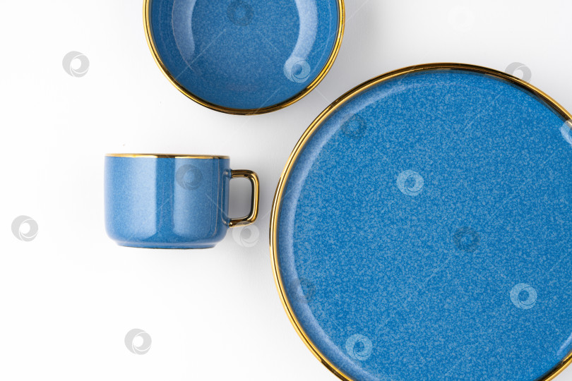 Скачать Набор синих керамических тарелок и чашек на белом фоне. Вид сверху фотосток Ozero