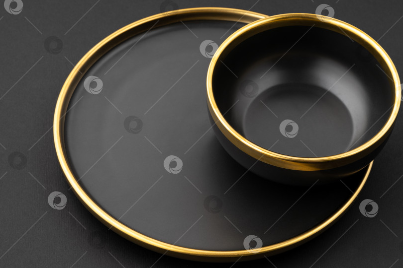 Скачать Набор из черной и золотистой керамической тарелки и миски на черном фоне фотосток Ozero