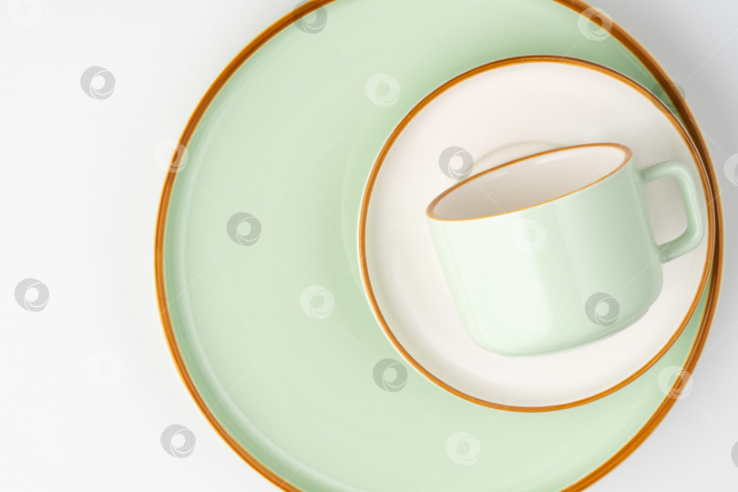 Скачать Набор белой и пастельно-зеленой керамической посуды с оранжевыми контурами фотосток Ozero