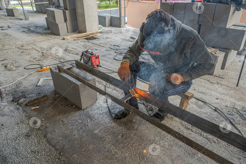 Скачать Работающий сварщик изготавливает металлическую конструкцию в новом здании инфраструктуры фотосток Ozero