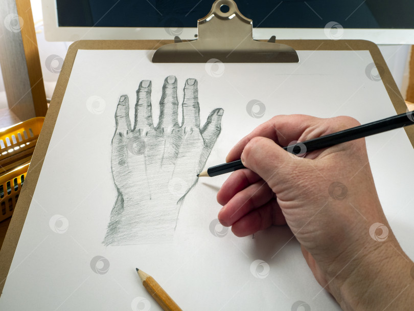 Скачать Карандашная рука рисует руку на бумаге. За планшетом для рисования находится монитор. Концепция онлайн-образования, онлайн-уроки рисования. фотосток Ozero