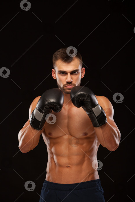 Скачать Мускулистый молодой человек с идеальным торсом с шестью кубиками пресса, в боксерских перчатках показывает различные движения и удары, изолированные на черном фоне с copyspace фотосток Ozero