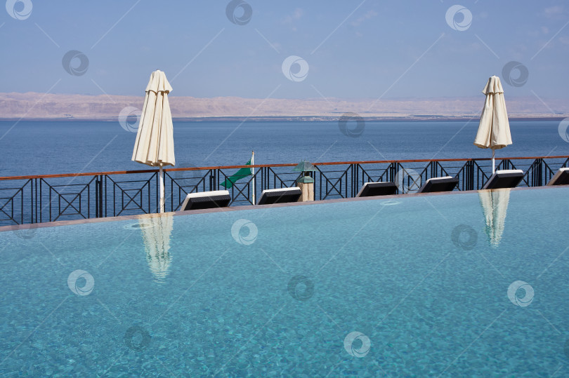 Скачать Винтажное фото. Май 2011 года. Мертвое море. Иордания. Отель Movenpick Resort and SPA Dead Sea 5*. Плавательный бассейн на берегу Мертвого моря. Размытый фон. Пляжные зонтики и шезлонги вдоль бассейна. фотосток Ozero