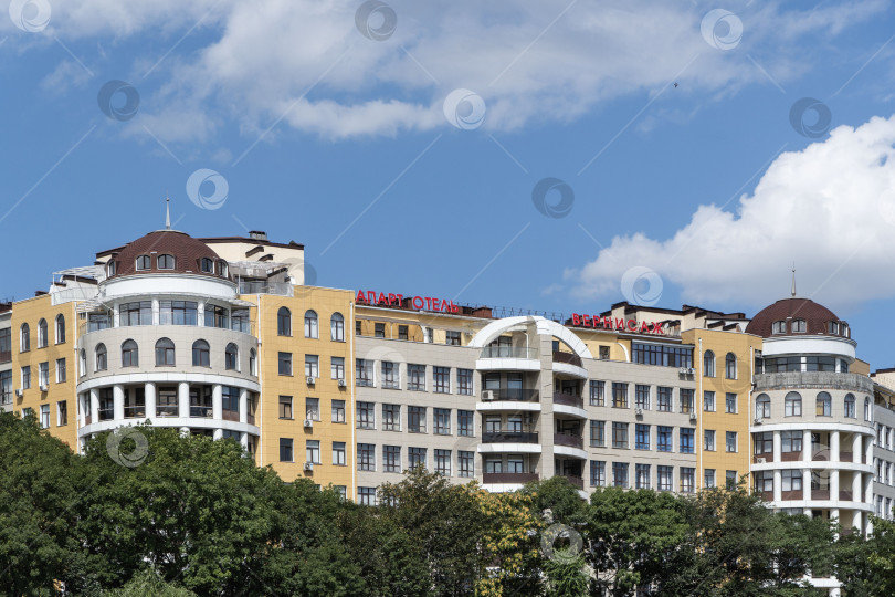 Скачать Современное здание апарт-отеля "Венрнисаж" в Кисловодске. Вид на отель с Курортного бульвара. По периметру отеля растут вечнозеленые растения. фотосток Ozero