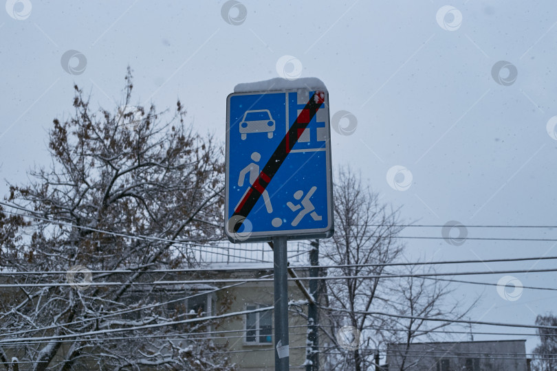 Скачать Сфотографируйте синий дорожный знак зимой на фоне многоэтажного здания. фотосток Ozero