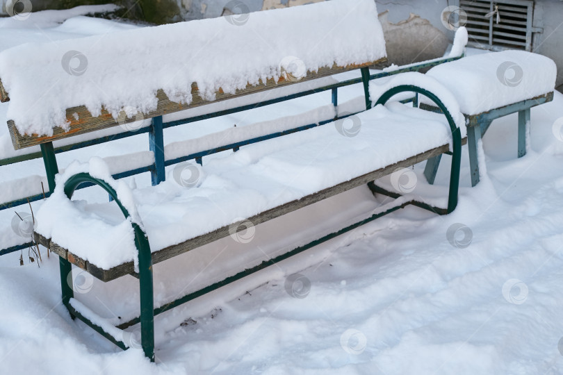 Скачать деревянная скамейка на снегу рядом с многоквартирным домом. фотосток Ozero