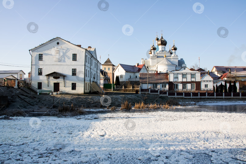 Скачать Белая церковь и дома на берегу реки, зимний пейзаж фотосток Ozero