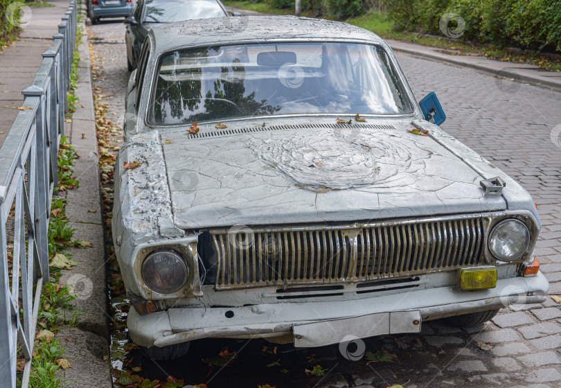 Скачать Старый ржавый автомобиль "Волга" стоит на брусчатой дороге фотосток Ozero