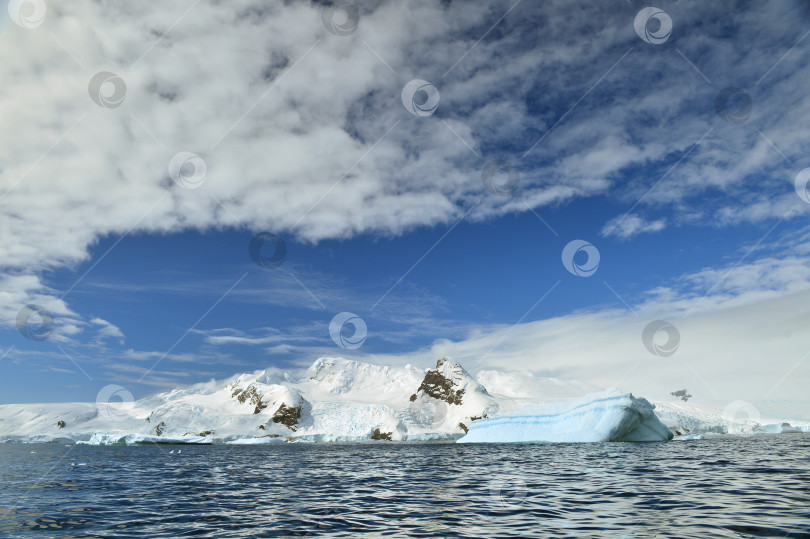 Скачать Айсберг на фоне ледника и голубого неба с перистыми облаками фотосток Ozero