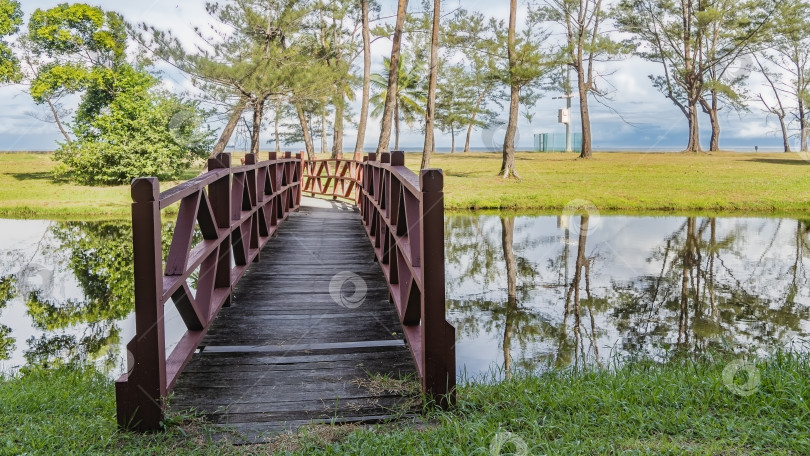 Скачать Через реку перекинут пешеходный деревянный мост с перилами. фотосток Ozero