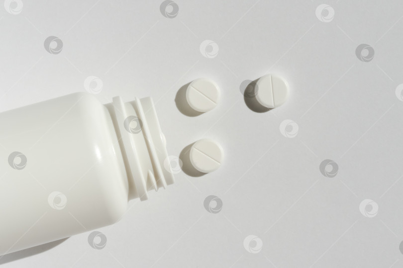 Скачать Белые таблетки из пластиковой бутылочки для лекарств на фоне с пробелом для копирования. Концепция медицины и здоровья фотосток Ozero
