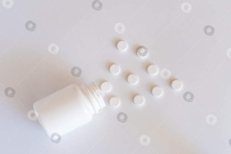 Скачать Белые таблетки из пластиковой бутылочки для лекарств на фоне с пробелом для копирования. Концепция медицины и здоровья фотосток Ozero