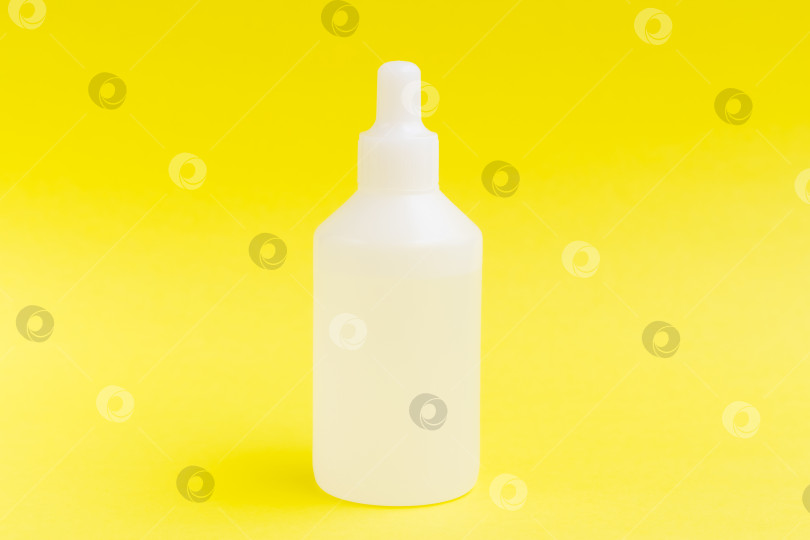 Скачать Бутылка с жидкостью на желтом фоне, концепция здоровья и медицины. фотосток Ozero