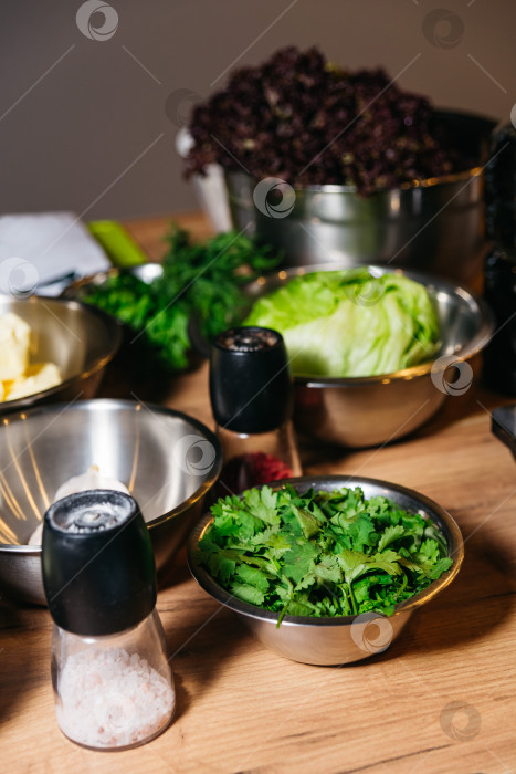 Скачать Свежая зелень и солонки на кухонном столе фотосток Ozero