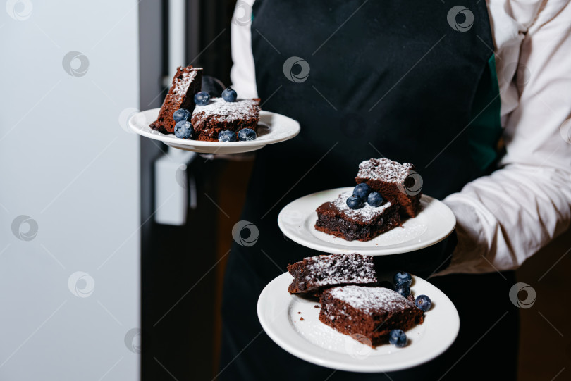 Скачать Официант подает тарелки с шоколадным тортом с черникой фотосток Ozero