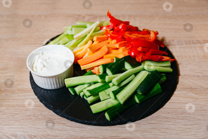 Скачать Черная грифельная доска, украшенная овощными палочками и соусом из сметаны фотосток Ozero