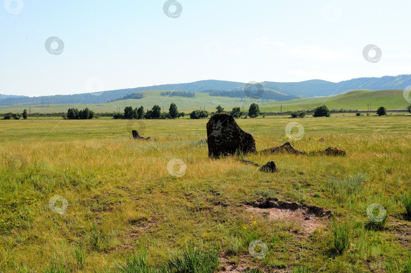 Скачать Древние менгиры, могильные камни в разрушенном кургане в бескрайней степи под ясным летним небом. фотосток Ozero
