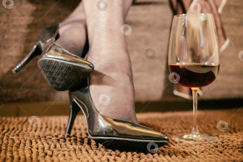 Скачать женские ноги в черных блестящих туфлях на высоком каблуке крупным планом и бокал вина на полу в комнате фотосток Ozero