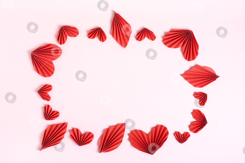 Скачать Рамка из сложенных красных бумажных сердечек и листьев на розовом фоне вид сверху фотосток Ozero