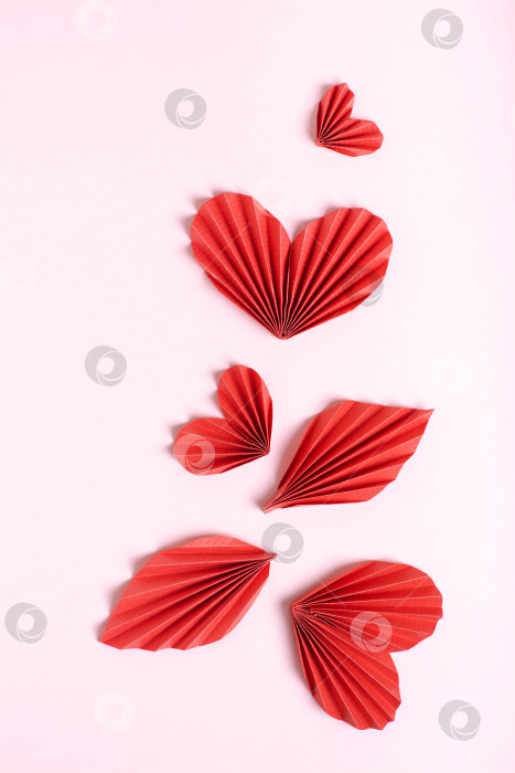 Скачать Красивая композиция из сложенных красных бумажных сердечек и листьев на розовом фоне вертикальный вид фотосток Ozero