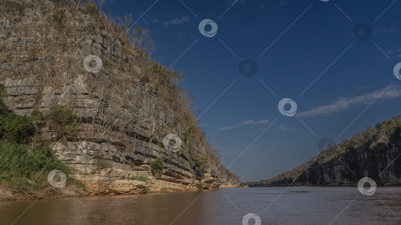 Скачать Спокойная красно-коричневая река течет между крутыми берегами. фотосток Ozero