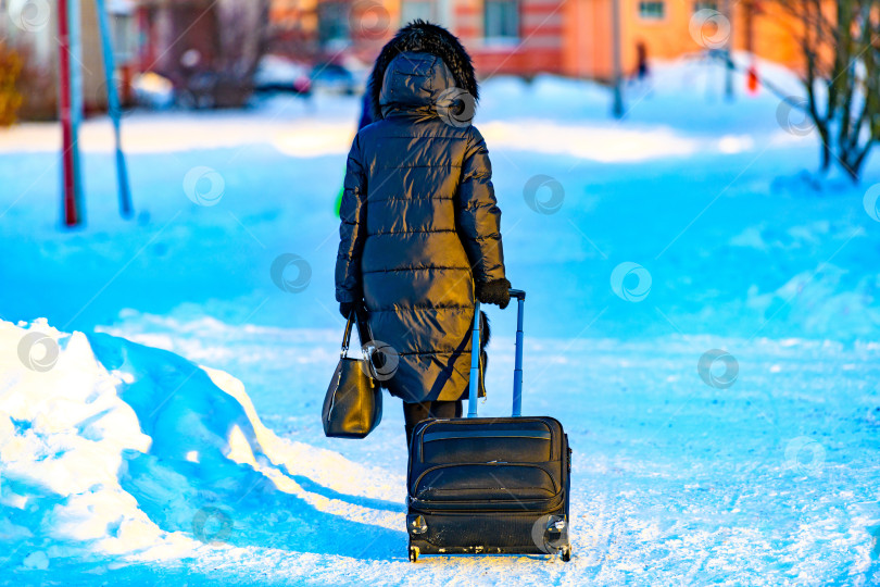 Скачать Женщина, путешествующая с чемоданом на фоне зимы.Поездка в жаркие и теплые страны холодной зимой. фотосток Ozero