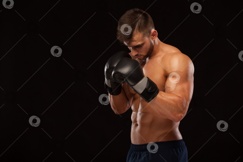 Скачать Мускулистый молодой человек с идеальным торсом и шестью кубиками пресса, в боксерских перчатках показывает различные движения и удары, изолированные на черном фоне с copyspace фотосток Ozero