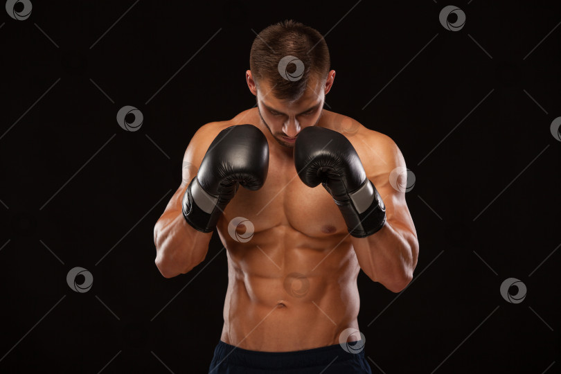Скачать Мускулистый молодой человек с идеальным торсом и шестью кубиками пресса, в боксерских перчатках показывает различные движения и удары, изолированные на черном фоне с copyspace фотосток Ozero