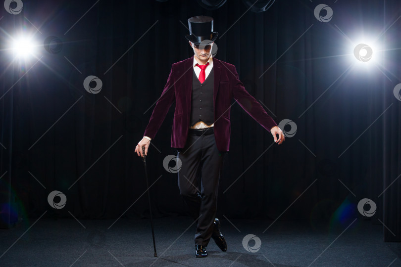 Скачать Фокусник, Жонглер, Забавный человек, Черная магия, Иллюзия, стоящий на сцене с тростью из прекрасного света фотосток Ozero