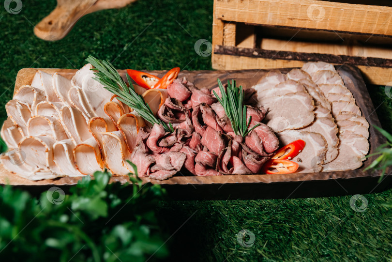 Скачать Блюдо из нарезанного мяса с розмарином на деревянной доске фотосток Ozero