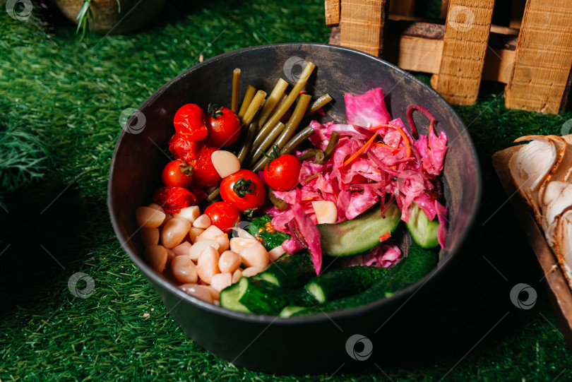 Скачать Ассорти из маринованных овощей в миске по-деревенски на искусственной траве фотосток Ozero